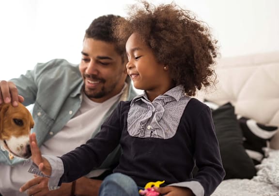 A man and a girl are sitting on a couch with a dog.