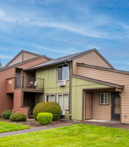 A house with a brown and green exterior and a well-maintained lawn.