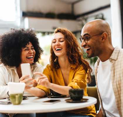 Three people are sitting at a table, laughing and enjoying each other's company.