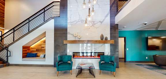 a lobby with two chairs and a coffee table in front of a fireplace