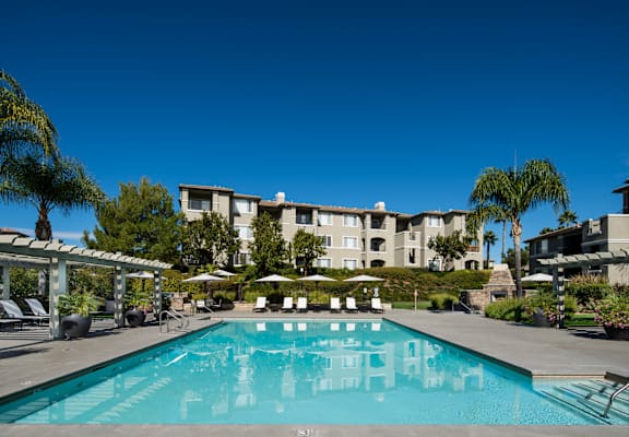 A large swimming pool in front of a building with a clear blue sky.
