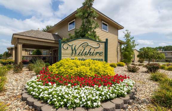 the welcome sign and flowers in front of a building