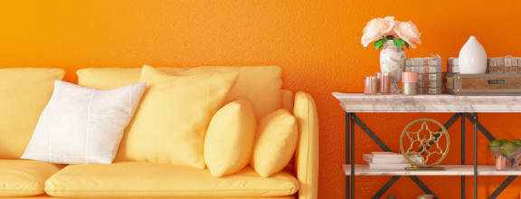 a living room with an orange wall and a yellow couch