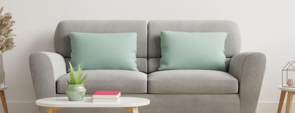 a gray couch with two green pillows in a living room