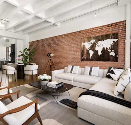 A living room with a white couch and a wooden chair.