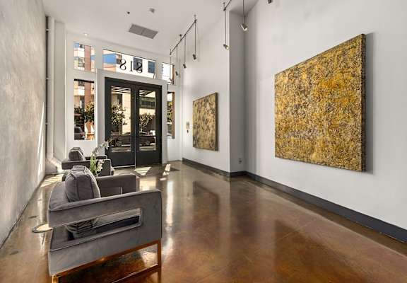 A room with a brown floor and a painting on the wall.