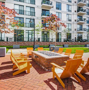 A set of yellow chairs and a table are arranged on a brick patio.