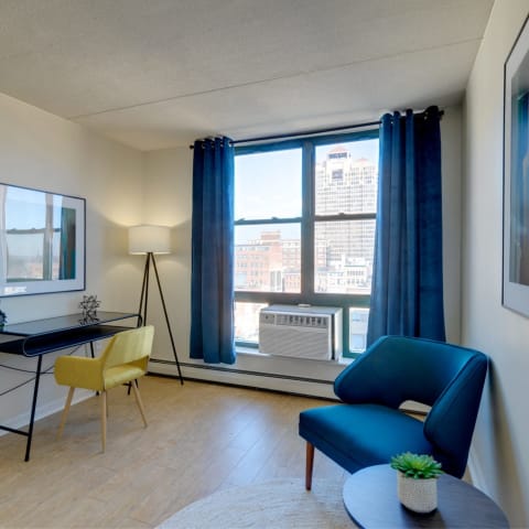 Home office with a blue chair and a desk and a window at Ninth Square Apartments.