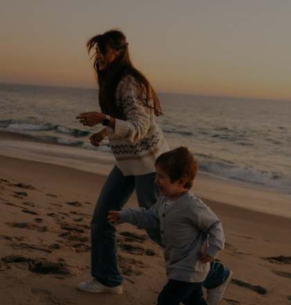 a mother playing with her son on the beach at sunset