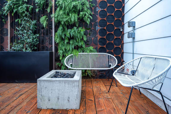 a patio with a chair and a table and a concrete fire pit