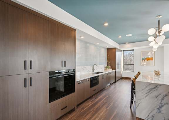 A modern kitchen with wooden cabinets and marble countertops.