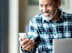 A man in a plaid shirt is smiling while looking at his phone.