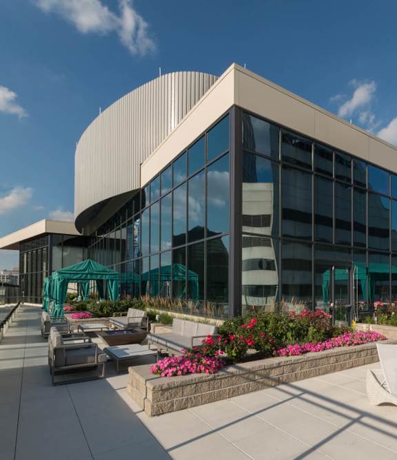 A modern building with a glass facade is surrounded by a well-manicured garden with pink flowers at 73 East Lake, Illinois, 60601