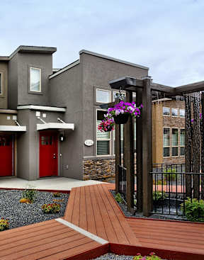A modern living room with a fireplace and a kitchen in the background at Verraso Village Townhomes in Meridian, 83646