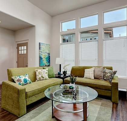 A living room with a green couch and a glass coffee table.