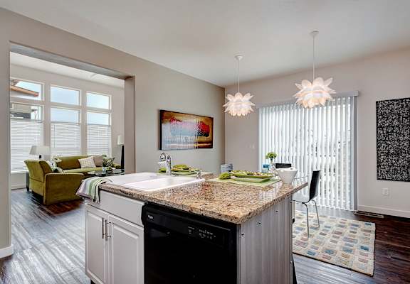 A kitchen with a granite countertop and a dining area with a table and chairs.