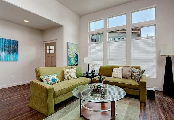 A living room with a green couch and a glass coffee table.