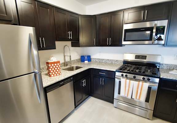 A kitchen with black cabinets and a stainless steel refrigerator.
