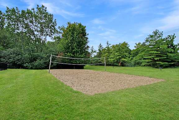 A volleyball net is set up in the middle of a grassy field.