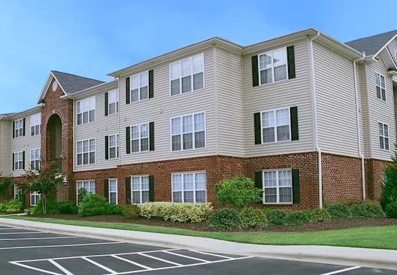 Apartment building with a parking lot in front.