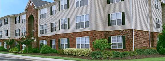 Apartment building with a parking lot in front.