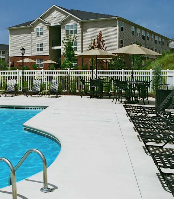 A pool with a metal ladder and a building in the background.
