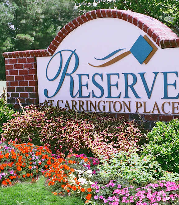 A sign that says Reserve Carrington Place in front of flowers.
