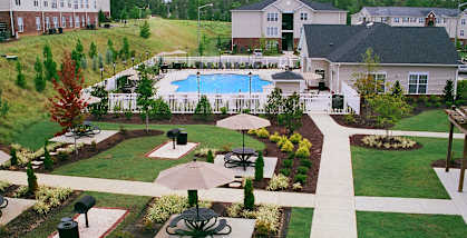 A large outdoor swimming pool surrounded by a grassy area and a fence.