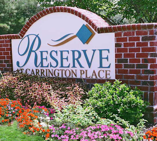 A sign that says Reserve Carrington Place in front of flowers.