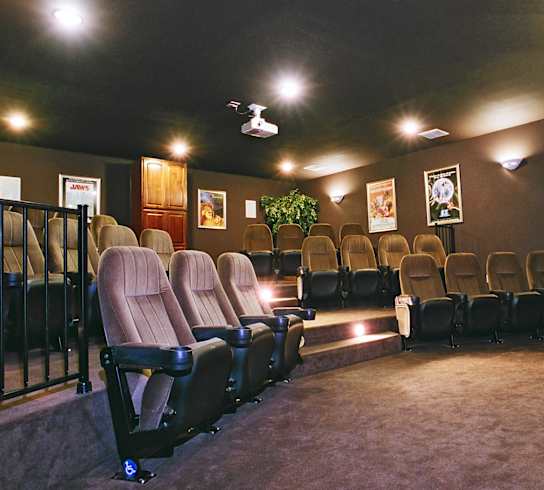 A row of seats in a dark room with a red exit sign.