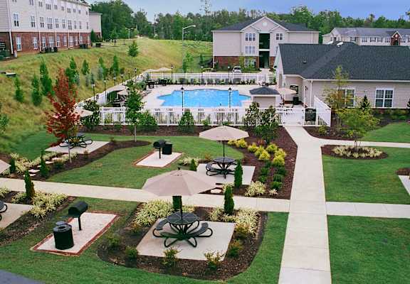 A large outdoor swimming pool surrounded by a grassy area and a fence.