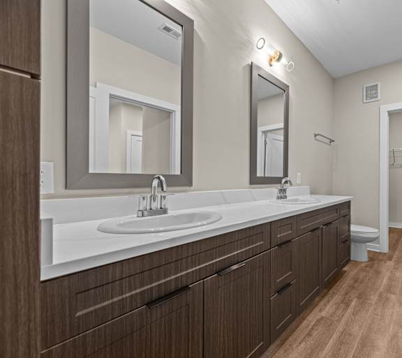 A bathroom with a sink, mirror, and wooden floors.