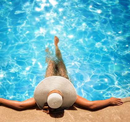A person wearing a white hat is floating in a pool.