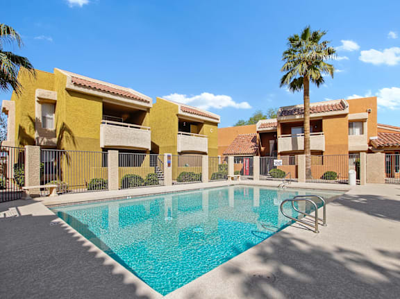 A swimming pool in front of a building with a palm tree.