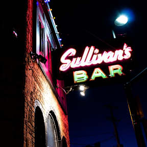 A neon sign for Sullivan's Bar is lit up at night.