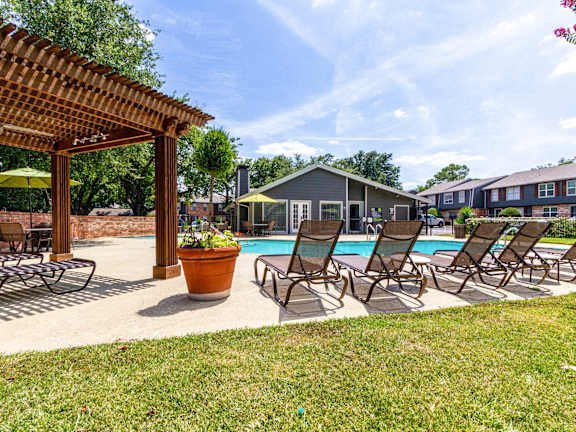 A patio with a couch, chairs, and a table with a tree in the background.