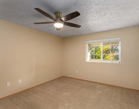 Empty room with a ceiling fan and a window.