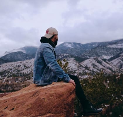 a man sitting on a rock overlooking the mountains