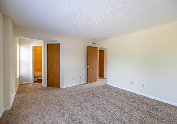 A room with carpeted floor and three doors.
