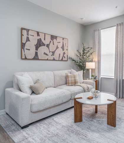 A living room with a white couch, a coffee table, and a painting on the wall.