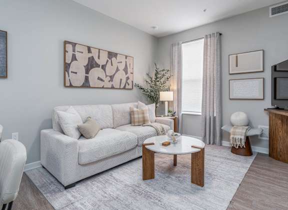 A living room with a white couch, a coffee table, and a painting on the wall.