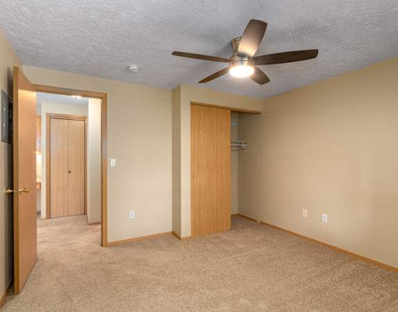 A room with a ceiling fan and two doors.
