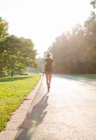 A woman is walking down a path in a park.