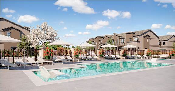 A large swimming pool surrounded by lounge chairs and umbrellas in front of a building.