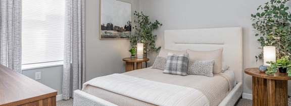 A bedroom with a large bed, a wooden nightstand, and a painting on the wall.
