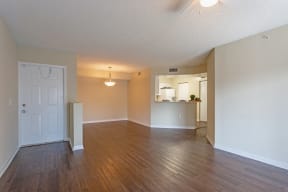 Photo of vacant apartment showing dark wood flooring, open dining area and kitchen