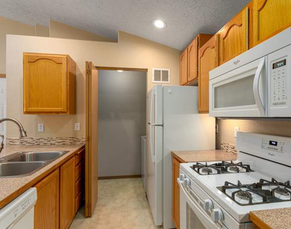 A kitchen with wooden cabinets and white appliances.