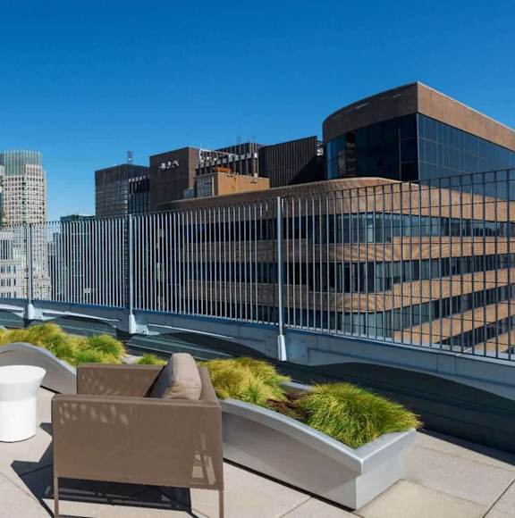 A rooftop patio with a table and chairs overlooking a city skyline. at The Metropolis, New York, NY, 10017