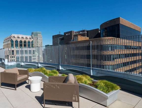 A rooftop patio with a table and chairs overlooking a city skyline.