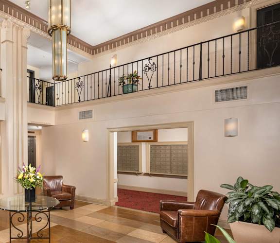 A large room with a balcony, a table with chairs, and a plant.